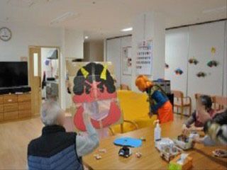 手作りの赤鬼の飾りに豆を投げている老人ホームの入居者