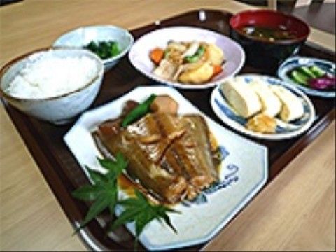 魚の煮付けやごはん、みそ汁、漬物、卵焼きが乗っているトレー
