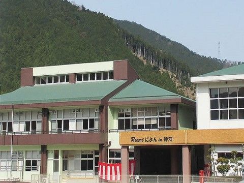 後ろに山があり、緑の屋根が特徴のグループホーム施設外観