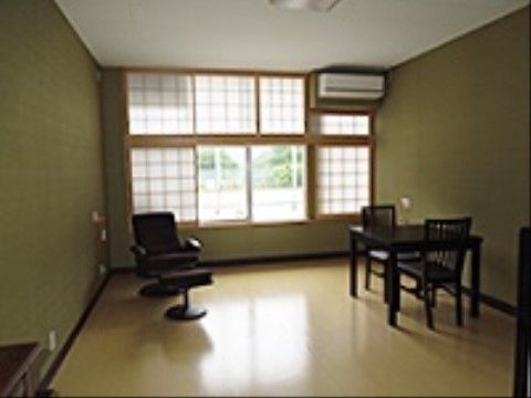 洋室にはエアコンが設置され、ソファ、テーブルと２脚の椅子が置いてあり、ガラス窓のほかに障子が設けられている。