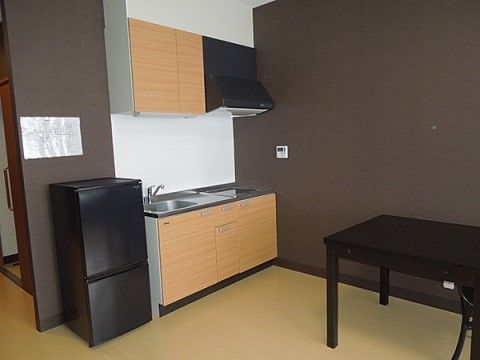 室内のキッチンには、流しと電磁調理器が整っており、キッチンの横には冷蔵庫が置かれ、テーブルも設置されている。