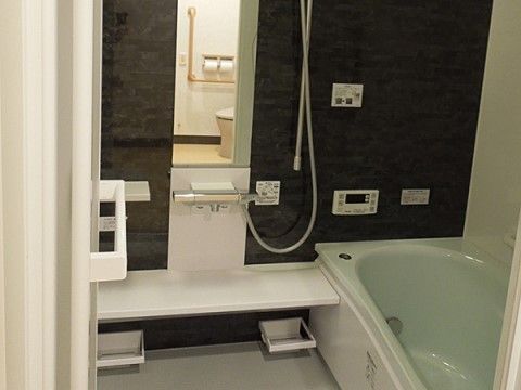 居室の浴室内は、カーテンによってトイレと区切られている。浴槽の横には鏡とシャワーが設置され、トイレの近くには手すりが設置されている。