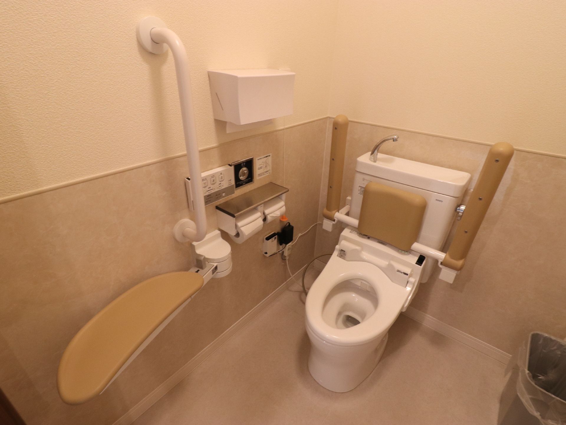 トイレの壁は、ベージュ色とオフホワイトの2トーンカラーになっている。ペーパーホルダーの上には、ペーパータオルも設置されている。