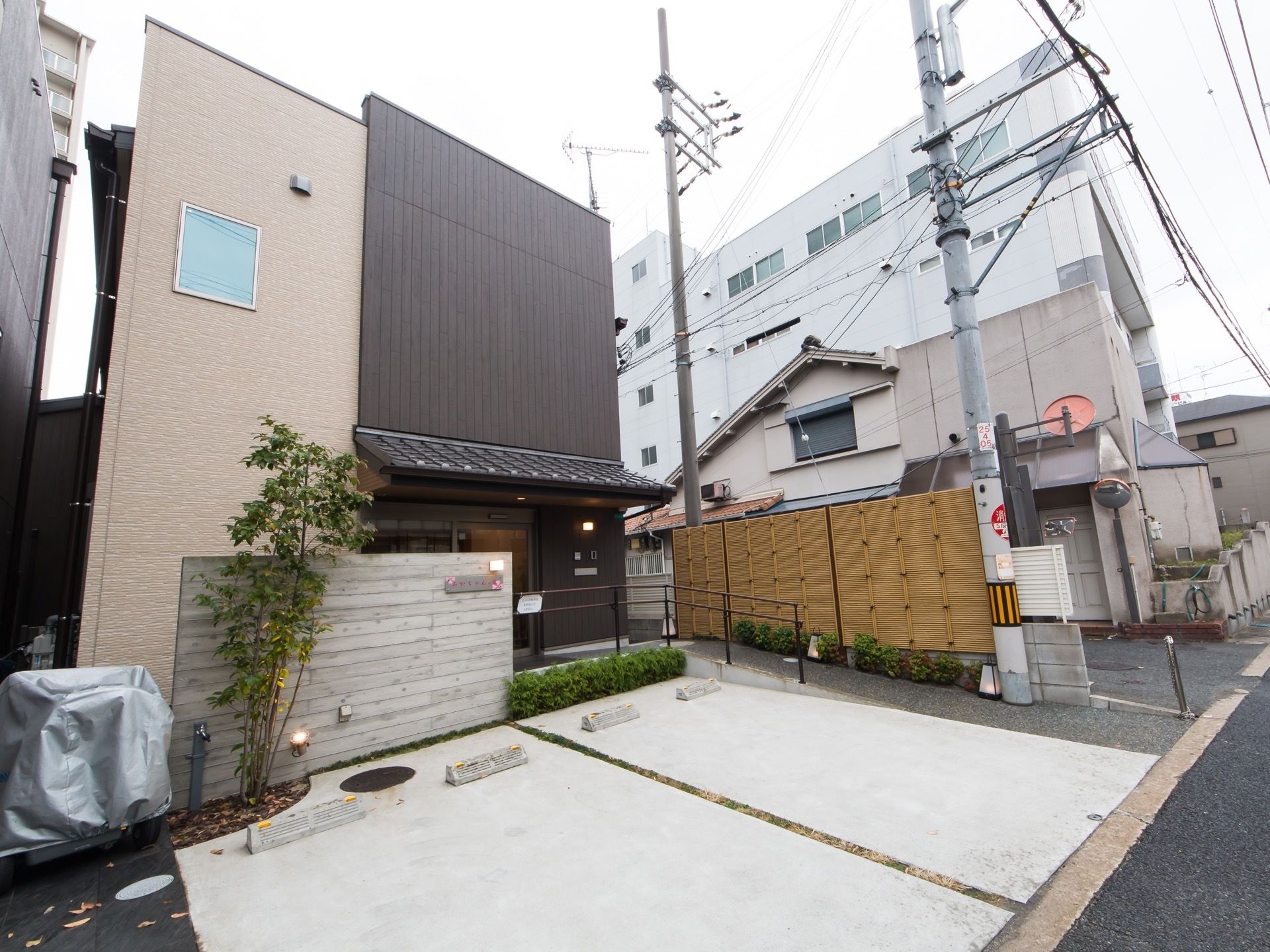 和風の２階建て家屋が建っている。玄関までは手すり付きのスロープがあり、２台分の駐車スペースも設けられている。