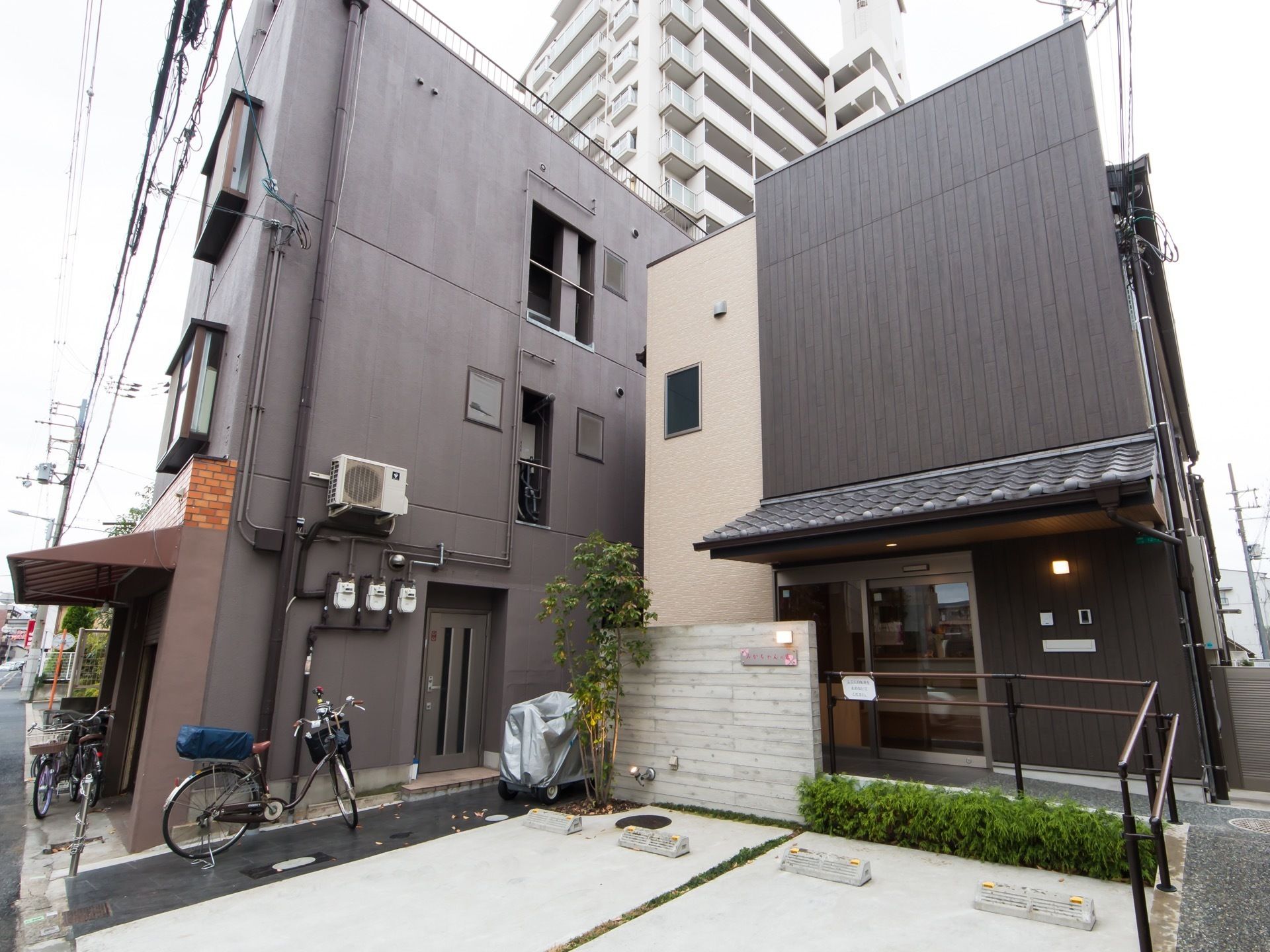 駐車スペースを備えた２階建て住宅が建っている。施設の周囲は、一戸建てや集合住宅が集まる住宅街である。