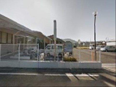 １階建ての白いレンガ調の建物。大きめの屋根付き駐輪場が併設されており、病院施設のすぐ前が広い駐車スペースになっている。