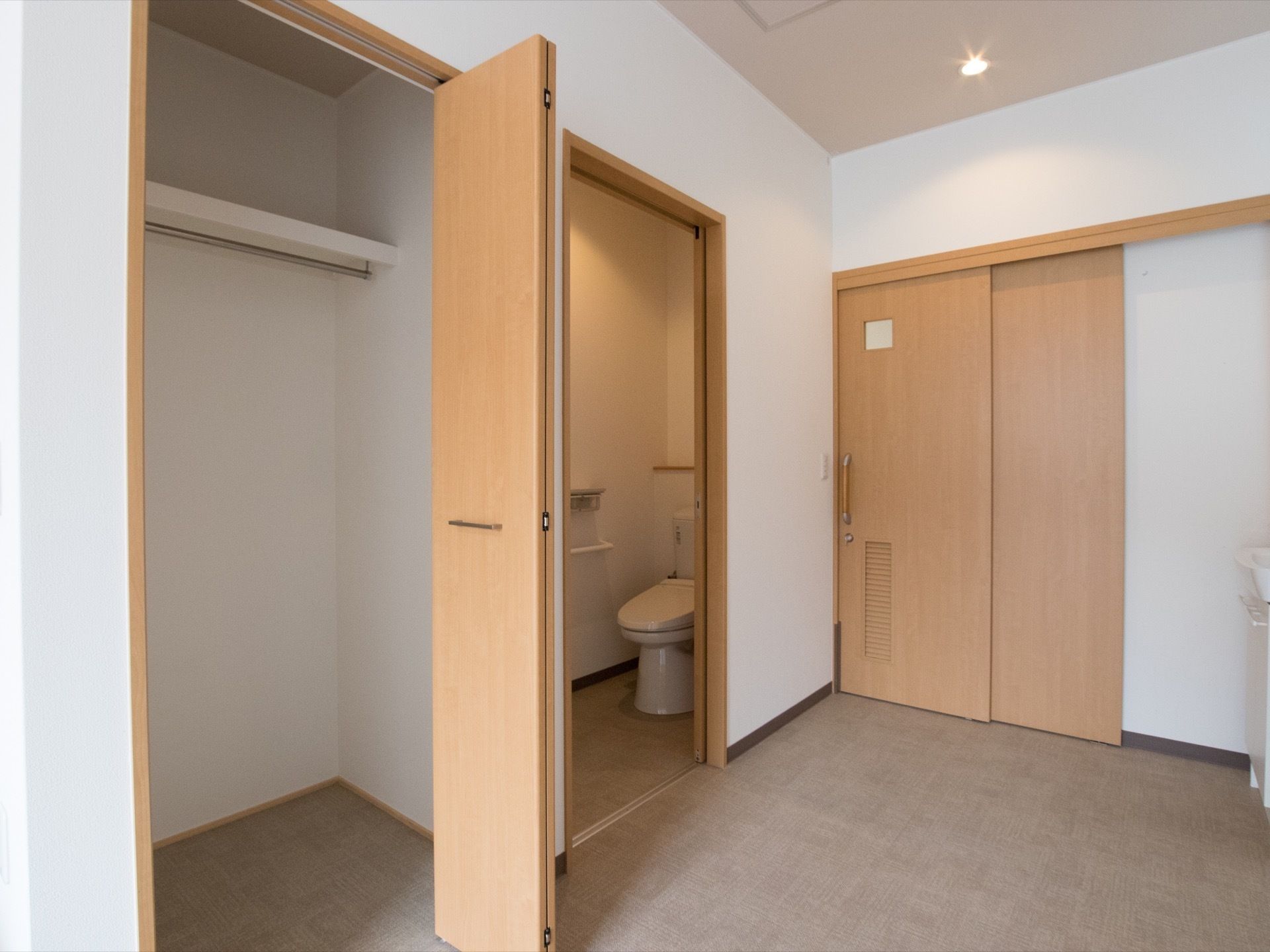 居室の入口は引き戸になっており、入ると右手にトイレがある。その隣には折れ戸式の大きな収納スペースが用意されている。