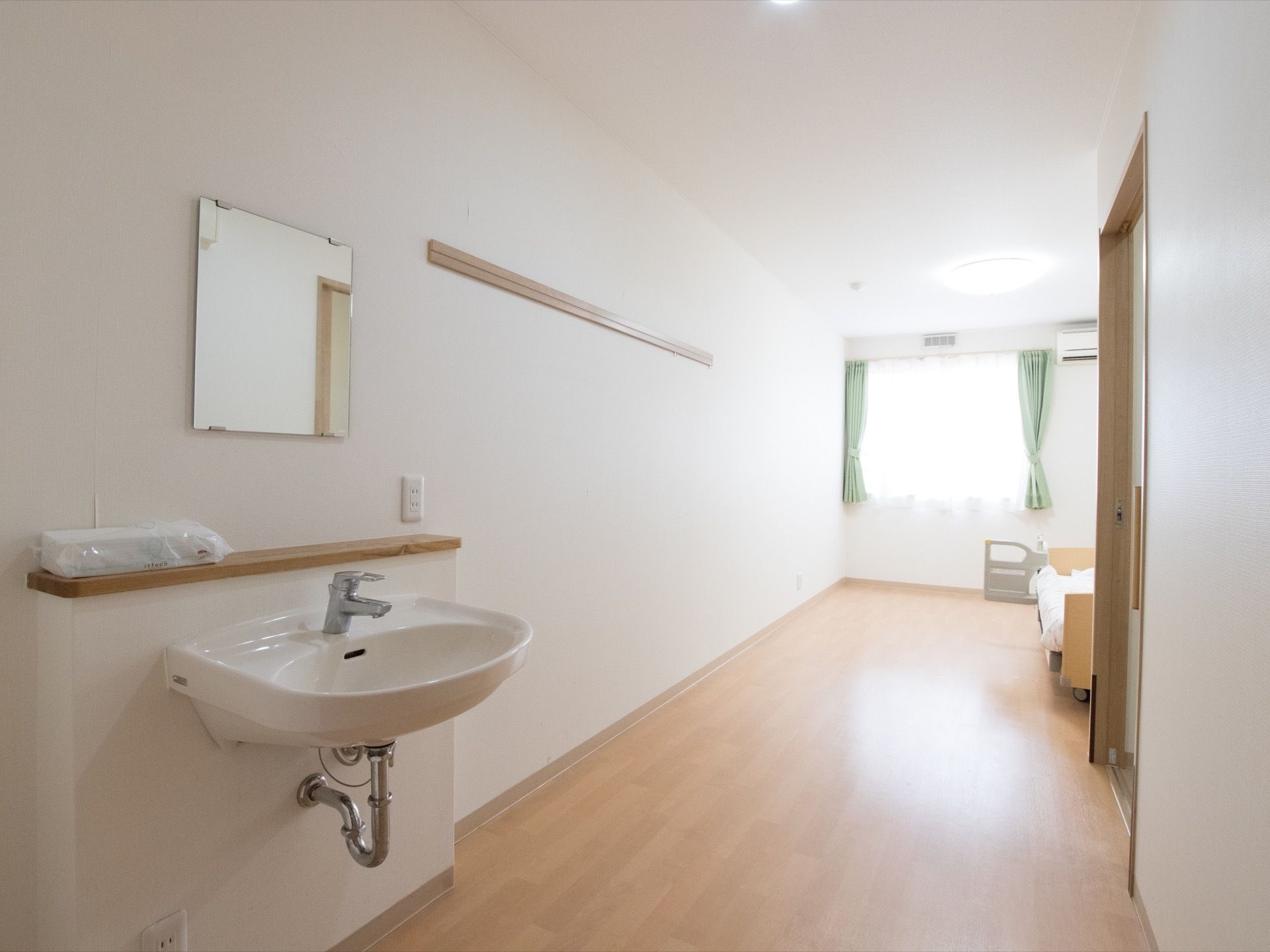 居室の玄関ドア付近にはシンプルな洗面台が用意されている。トイレ使用後の手洗いも兼ねられる場所に配置されている。