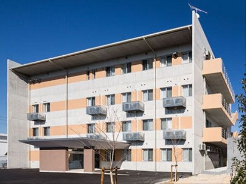 オレンジと白の壁が特徴のマンションタイプの施設外観