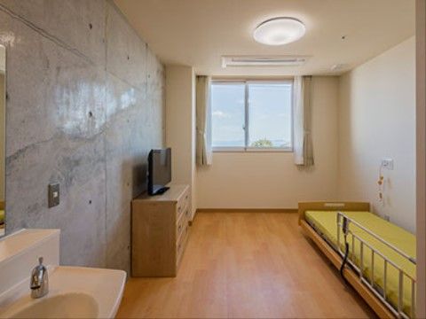 壁には白い壁だけでなく、コンクリートのような無機的な１面があるのが独特である。シンプルな家具を並べてモダンな雰囲気にできる。