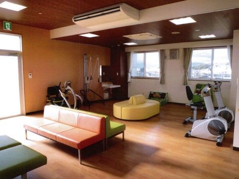 開放的なスペースにカラフルなソファーや、トレーニング機器が複数置かれている。床はフローリングとなっている。