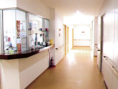 ガラス張りのスタッフルームが見える通路幅のある廊下である。カウンターの下には、消火器が置かれている。
