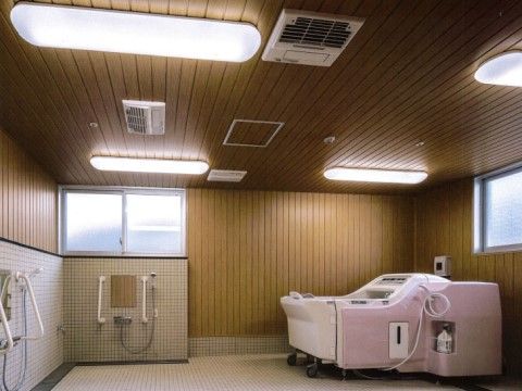木のぬくもりが感じられる天井に複数の照明が設置されている。床はタイル張りとなっており、浴室の上部には窓がある。