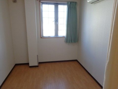 窓から光の入るシンプルな居室。明るめのフローリング床と白い壁の間には空間の印象を引き締める濃げ茶色のラインが入っている。