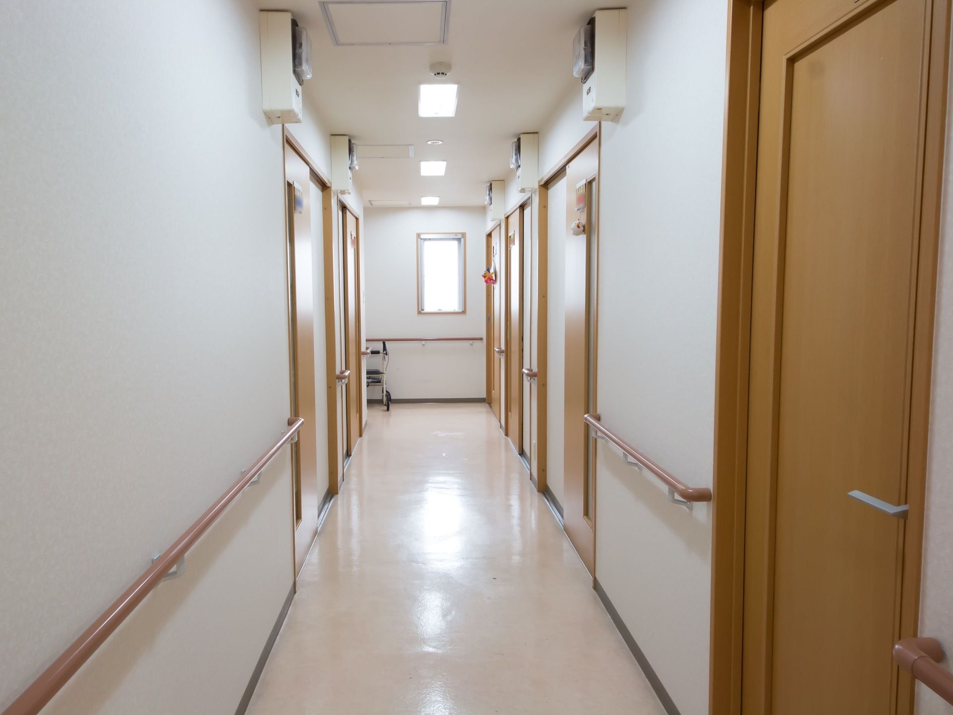 廊下の床は白く光沢のある材質になっている。天井には等間隔に照明が並び、火災報知機などが取りつけられている。