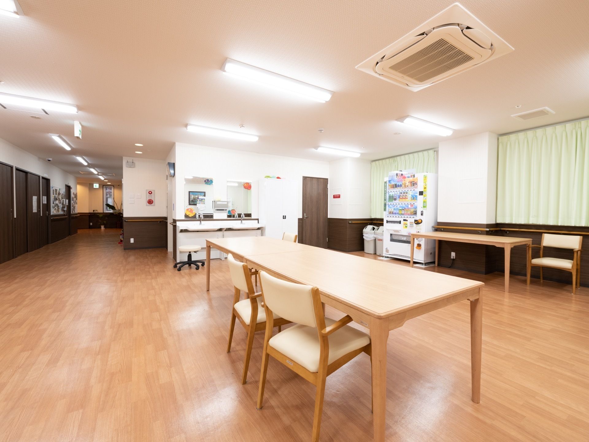居室前の廊下から開けたフロアーが共有スペースとなっている。洗面台が２面完備され、自動販売機が設置されている。