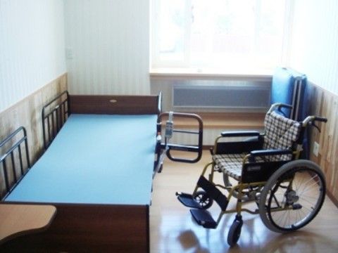 茶色のベッドと水色のマットレス、車椅子が置かれているお部屋