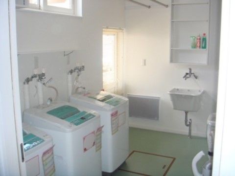 衣類の手洗いもできる広くて深めの流しがある。洗剤を置く棚も用意されている。洗濯機は３台用意されており待ち時間が少なくなるよう配慮されている。