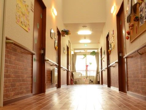 手作りの絵や折り紙で飾られた壁があるグループホームの廊下