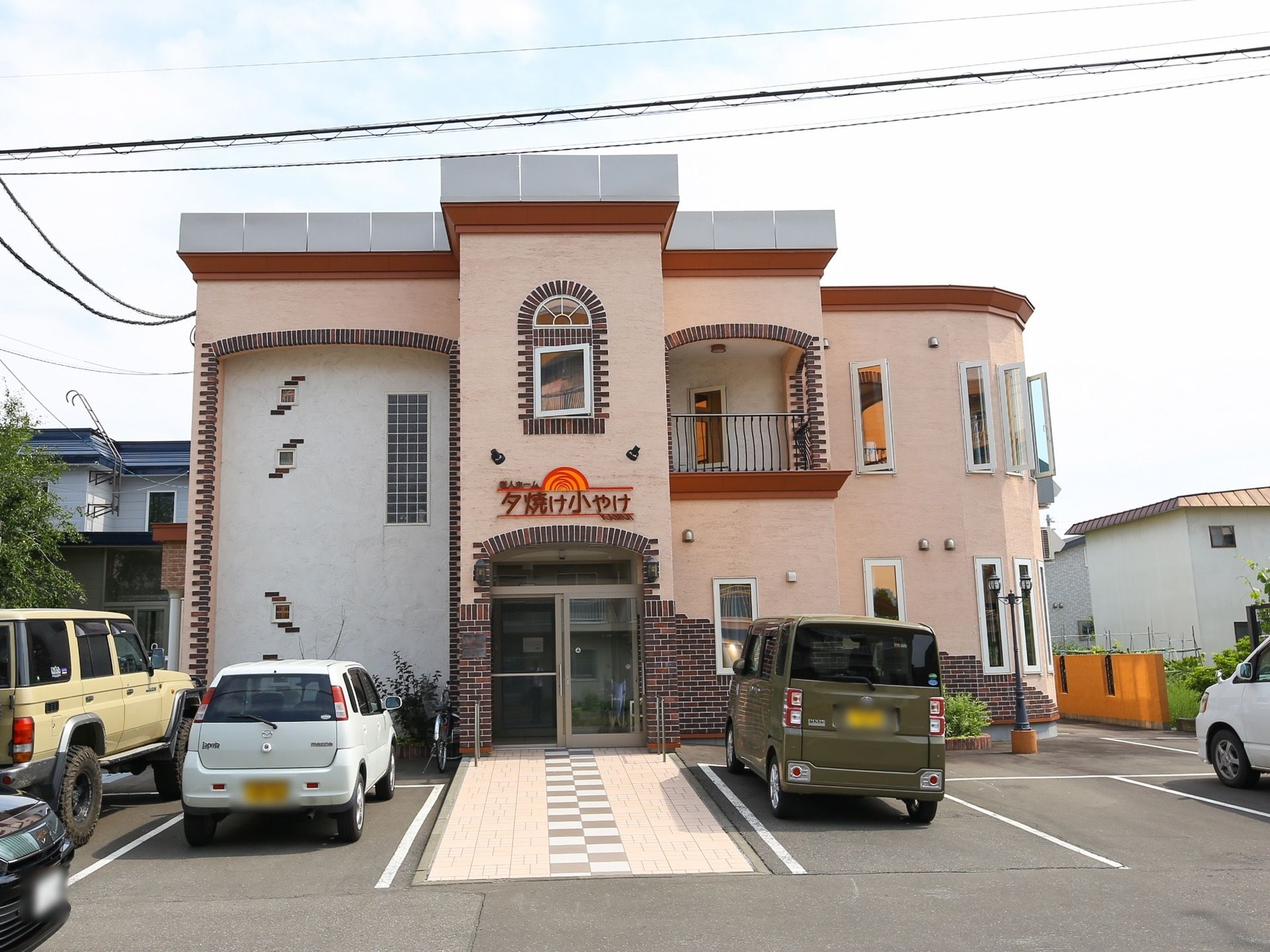 ほぼ正面から見た施設建物。壁はレンガ風の柄とクリーム色の漆喰のようなパネルを組み合わせたデザインになっている。