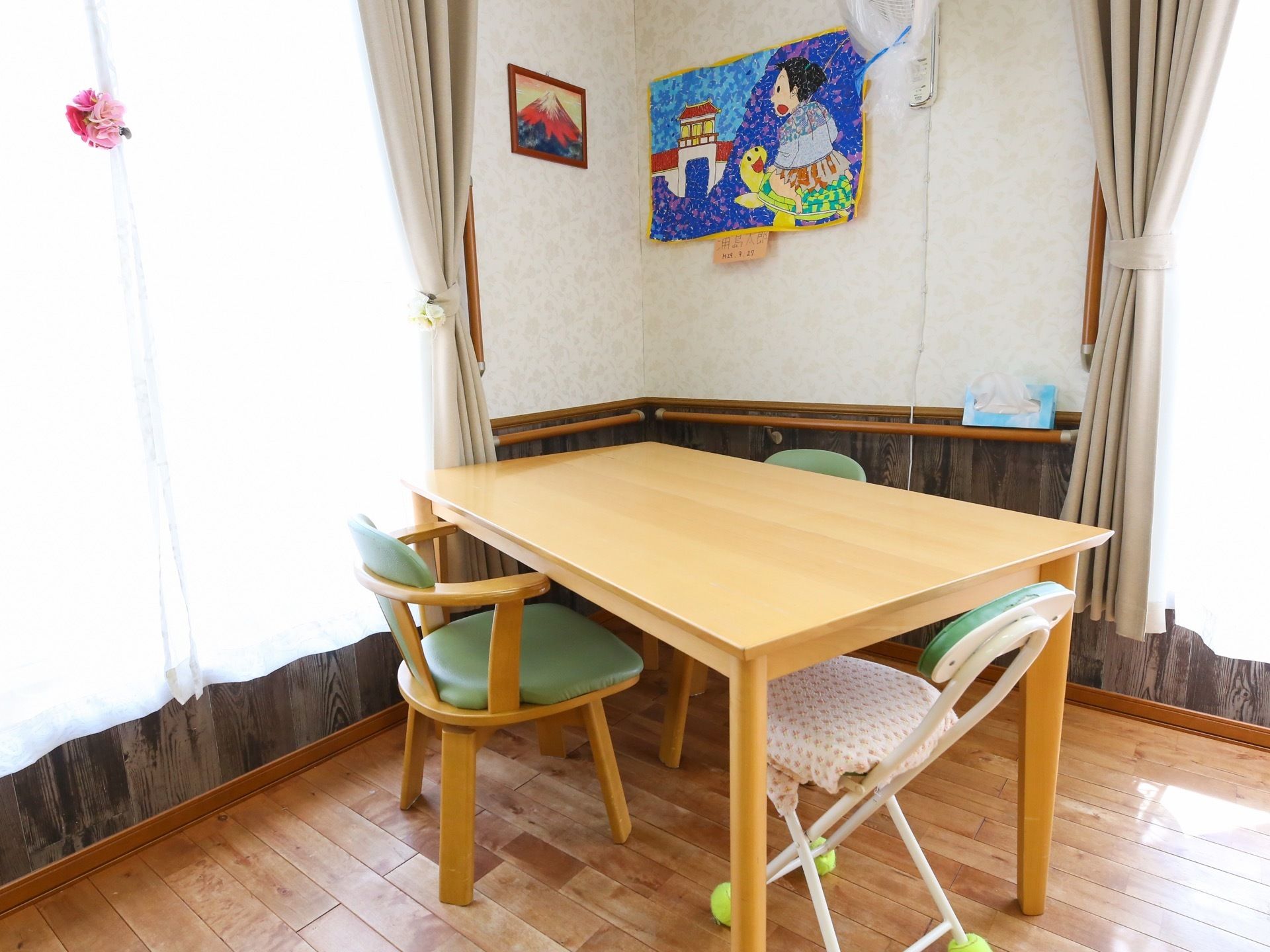 共有スペースには、座席としていくつかのテーブルを設置してある。壁には入居者様の手による作品が飾ってある。