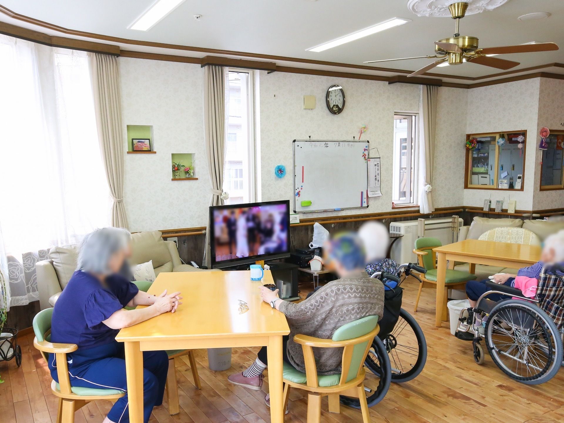 共有のリビングは食堂も兼ねている。室内には予定をメモするホワイトボードの掲示板やテレビなどが置かれている。
