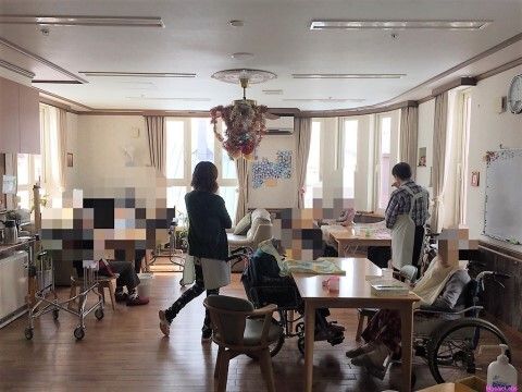 白い壁のお部屋に置かれている、青い車椅子とオレンジ色のベッド