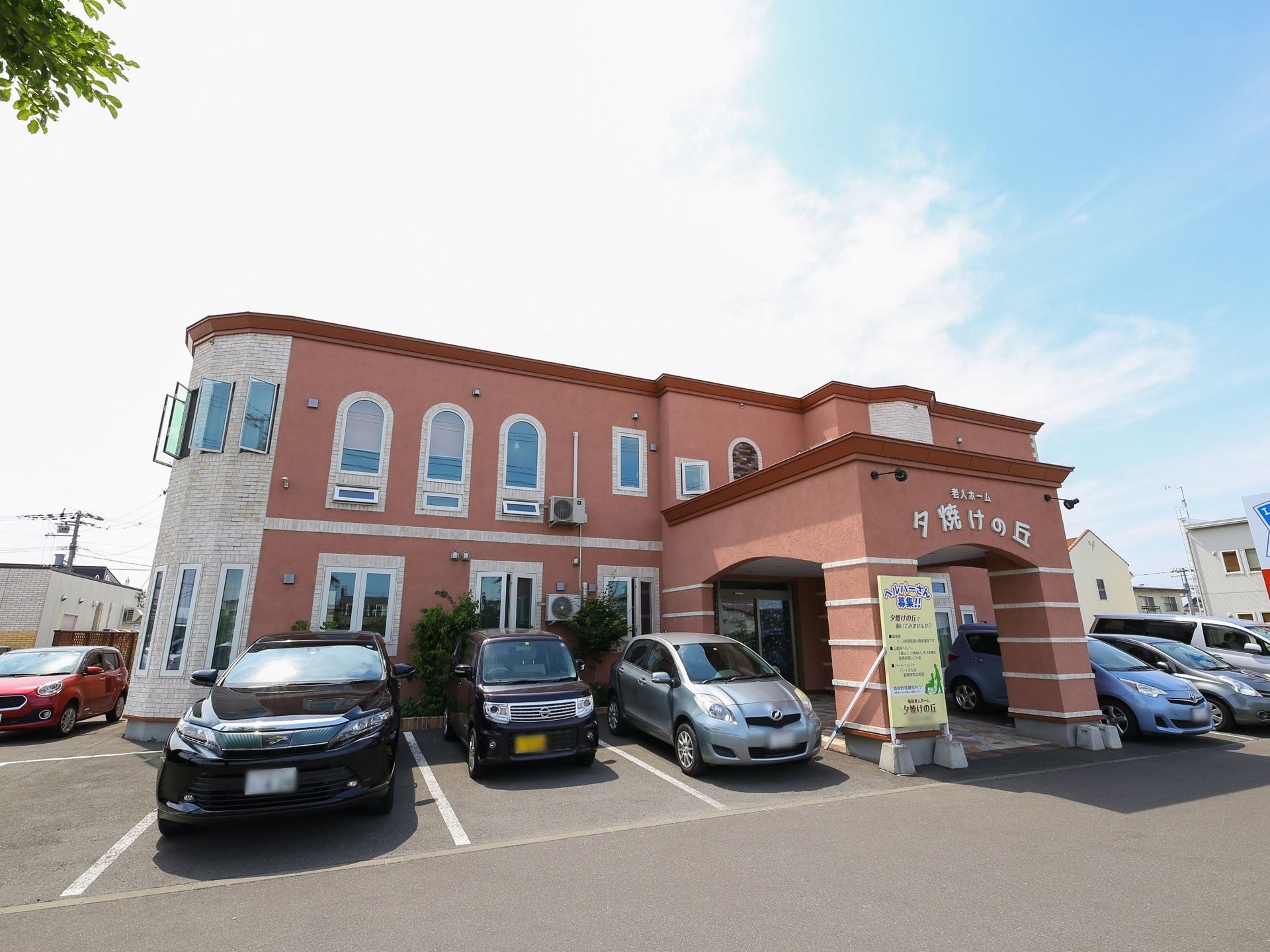 赤い塗り壁の２階建ての施設である。建物の周囲がアスファルトで舗装されており、複数の自動車が駐車してある。