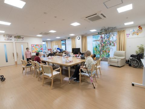 中央にダイニングテーブルセットがあり、座ってくつろぐ高齢者たち