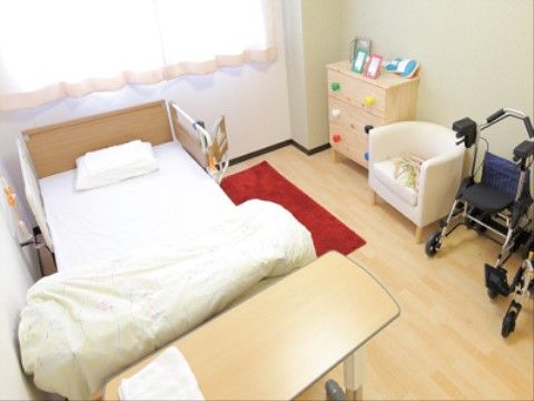 館内には、完全個室の居室が用意されている。ナースコールや介護ベッドが完備されている。収納家具や椅子、歩行車が置かれている。