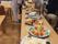 食堂に置かれたテーブルには、厨房でイベント用に作られた大皿料理が並べられている。調理スタッフが盛り付けをしている。