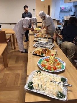 長いテーブルの上にある、大皿に乗ったサンドイッチなどの料理