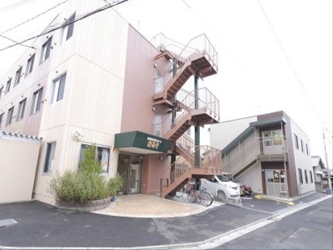 外階段があり、外に自転車が停まっている介護施設の外観