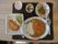 食事はカレーライス、とんかつ、サラダ、ヨーグルトなどが並んでいる。お箸と大小のスプーンが置かれている。