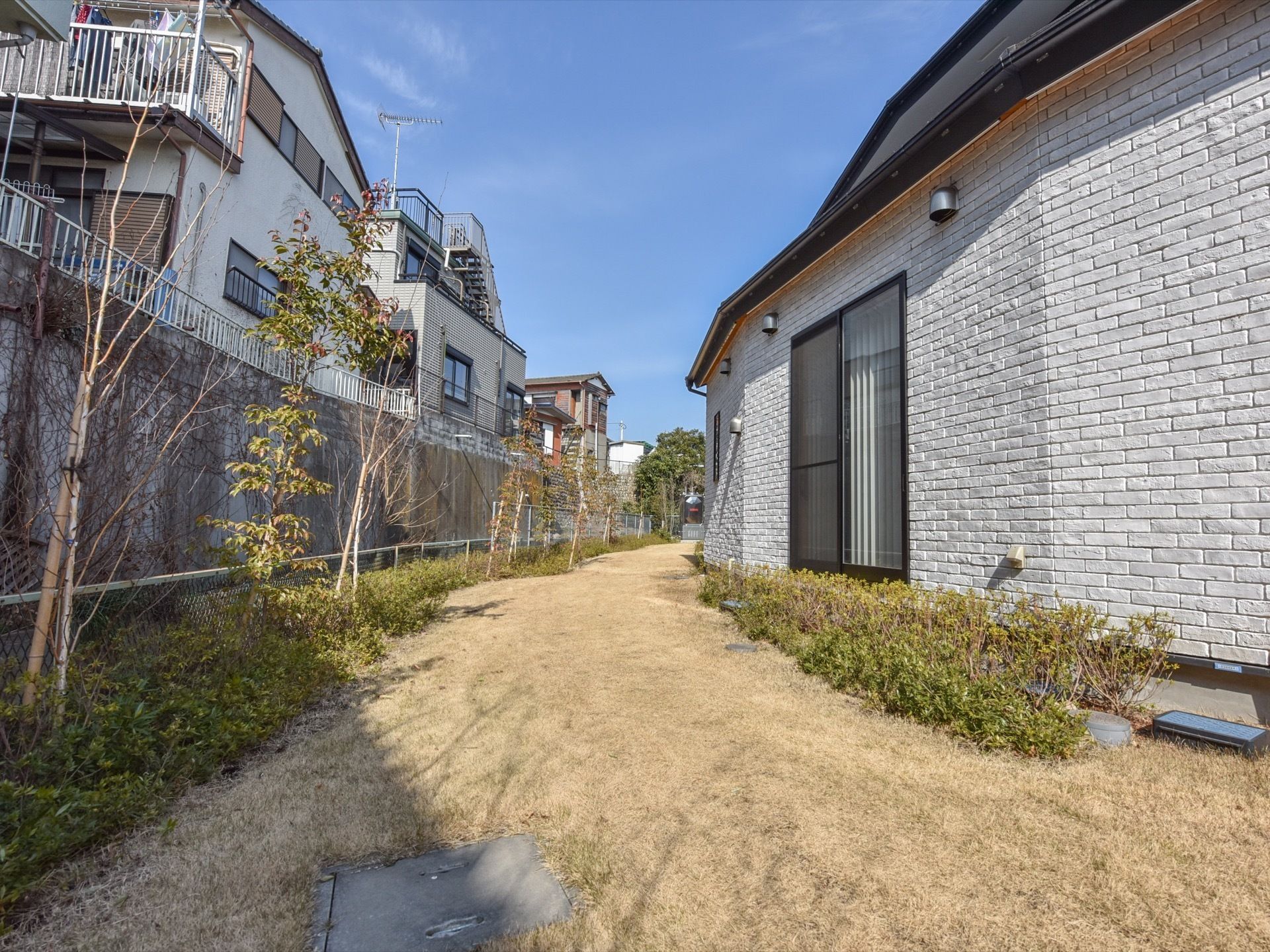 閑静な住宅街に建つ施設である。建物横の敷地内には芝生を敷き詰め、樹木を植えている。心和む緑豊かな空間である。