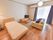 個人で生活する部屋にはベッドやテレビ、ソファなど生活用品が設置されている。窓が大きく、青色のカーテンが風になびいている。