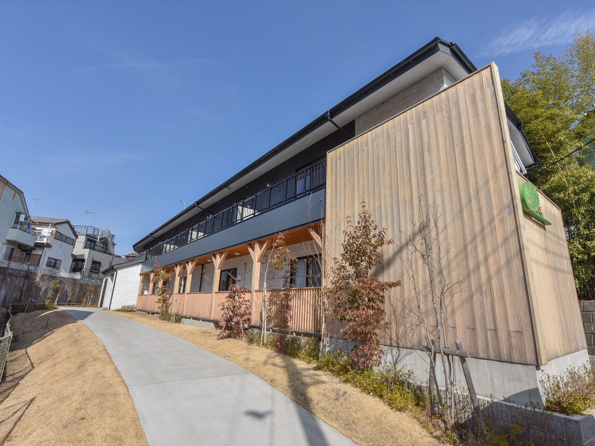 白いレンガ調の壁で、アパートタイプの施設は住宅街の中にある。ウッドテラスのようなベランダもついている。非常に綺麗な建物。