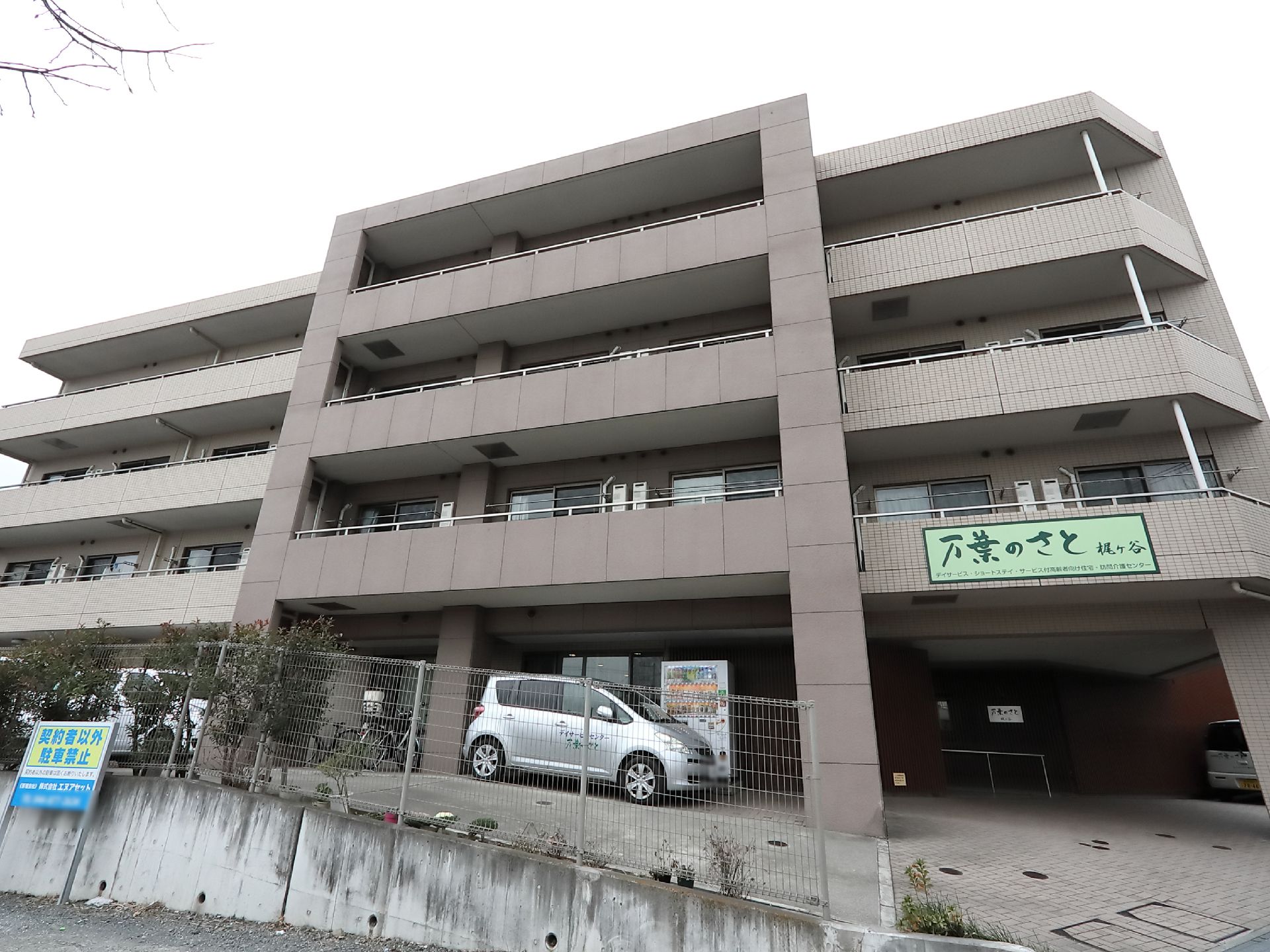 施設の敷地は、隣地からすると一段高くなっている。傾斜となる１階に駐輪、駐車のスペースが設けられている。