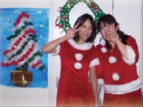 壁に貼られたクリスマスの絵と、サンタクロースの格好をしている女性二人