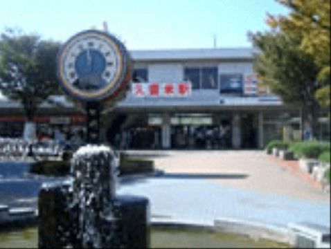 久留米駅正面の写真である。駅前の広場には大きな時計が立っており、サイドには木や花壇が設置されている。