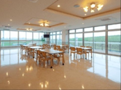 開放的なスペースにダイニングテーブルと椅子が複数置かれている。天井にデザイン性のある照明が取り付けてある。
