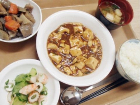 マーボ豆腐や煮しめ、きゅうりの酢の物、味噌汁、白ごはんである。噛み砕きやすいように柔らかく調理している。