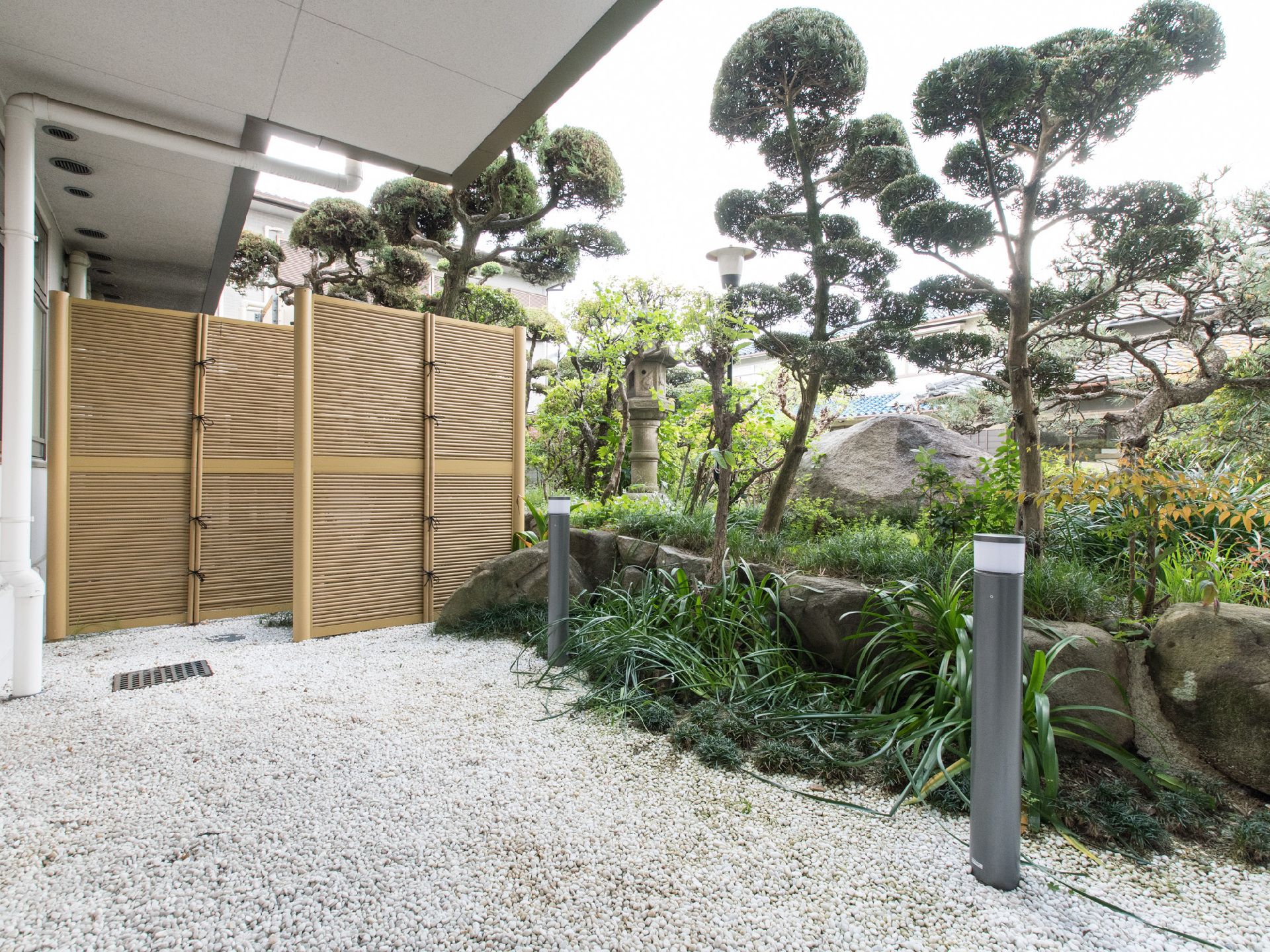 白い石が敷かれており、植木がある、老人ホームの庭園