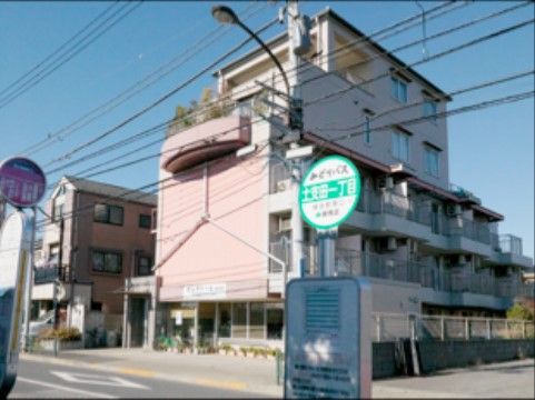 施設は５階建てのピンク色の建物である。バス通りに面した場所に建っているので、目の前にバス停が設置されている。