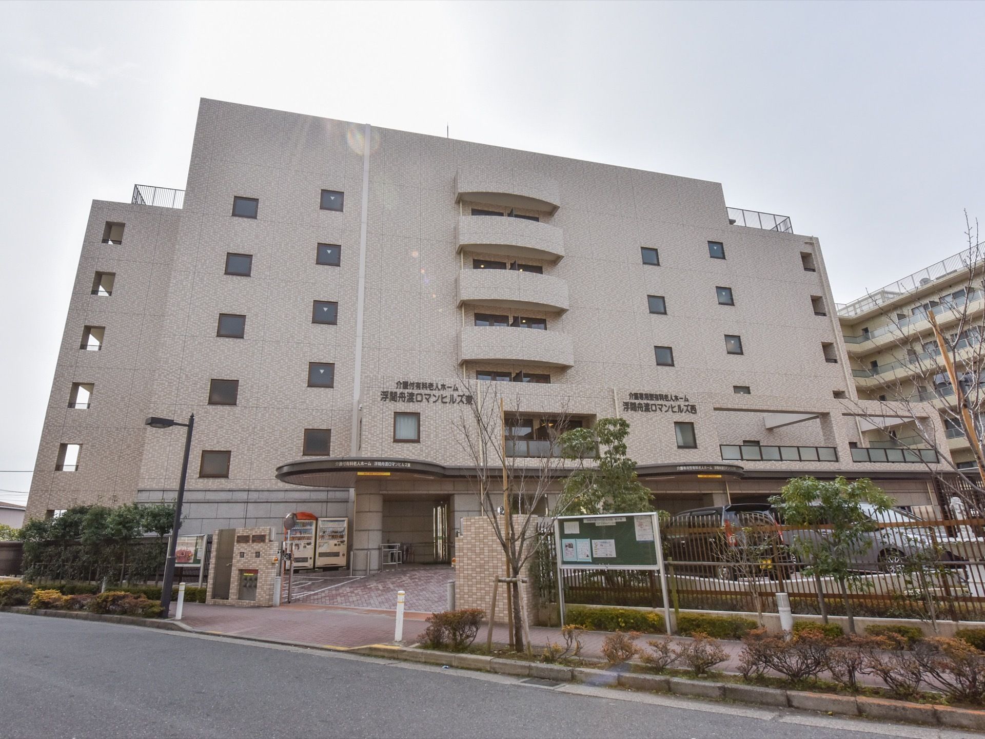道路に面した建てられている施設の外観。外壁は落ち着いたベージュ系になっている。敷地内に駐車場が完備している。