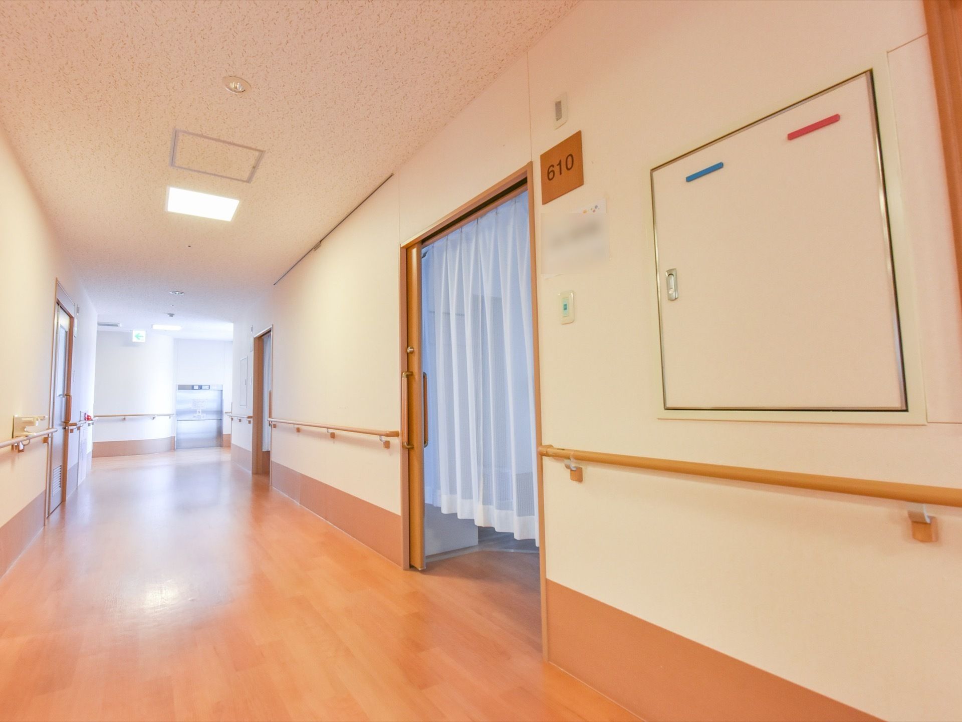 居室前の広々とした廊下。両サイドには手すりが設置されている。居室の扉の幅は広く、カーテンが掛けられている。