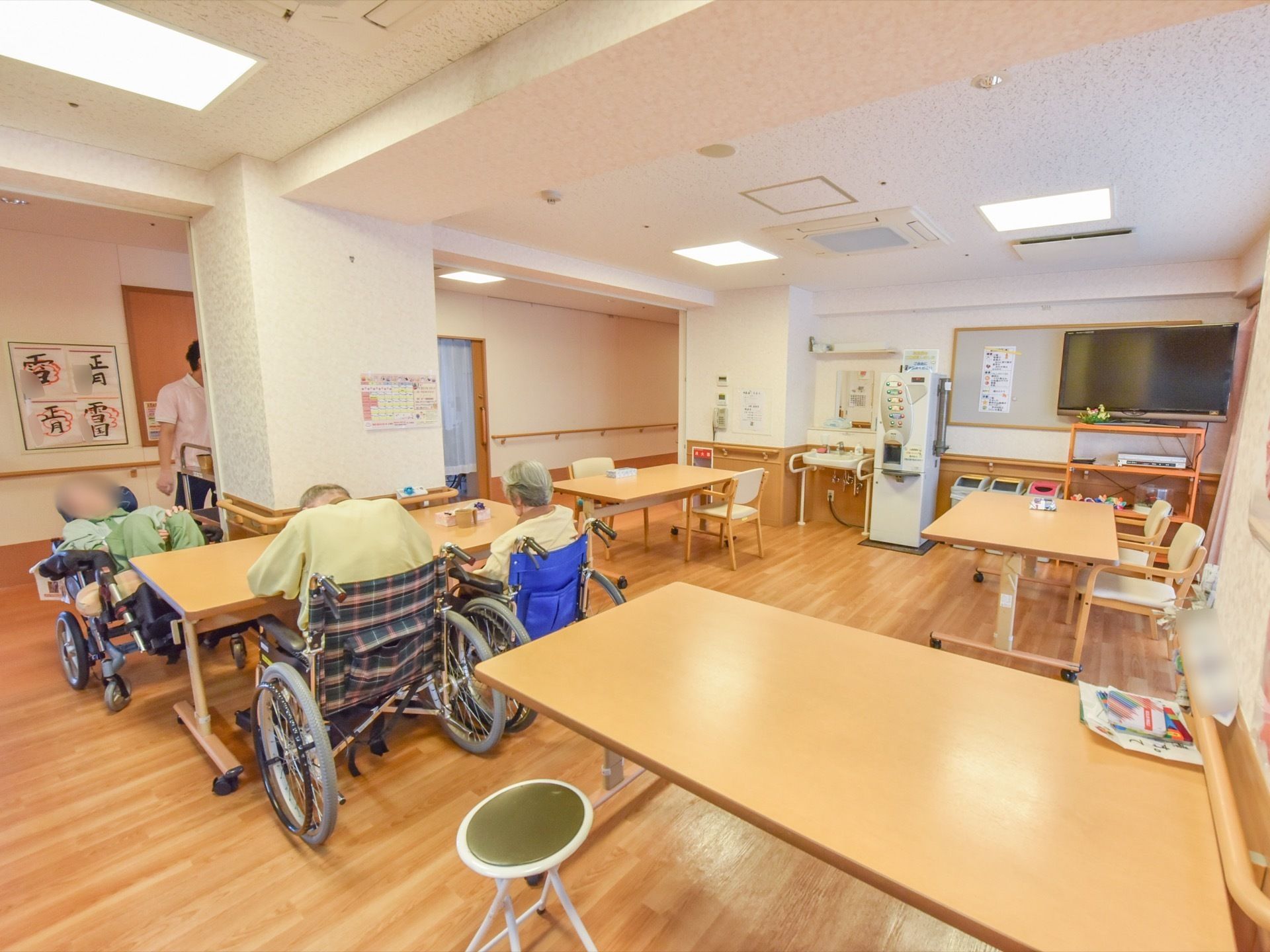 オープンタイプになっている共有スペース。大きめのテーブルがゆったりと置かれている。入居者様たちが集っている。