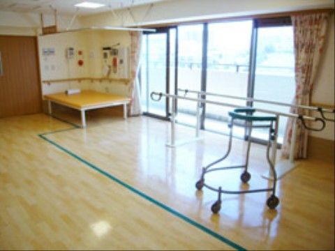掃出し窓を大きく確保した空間である。窓際にリハビリ用の手すりがあり、歩行を補助する器具が置かれている。