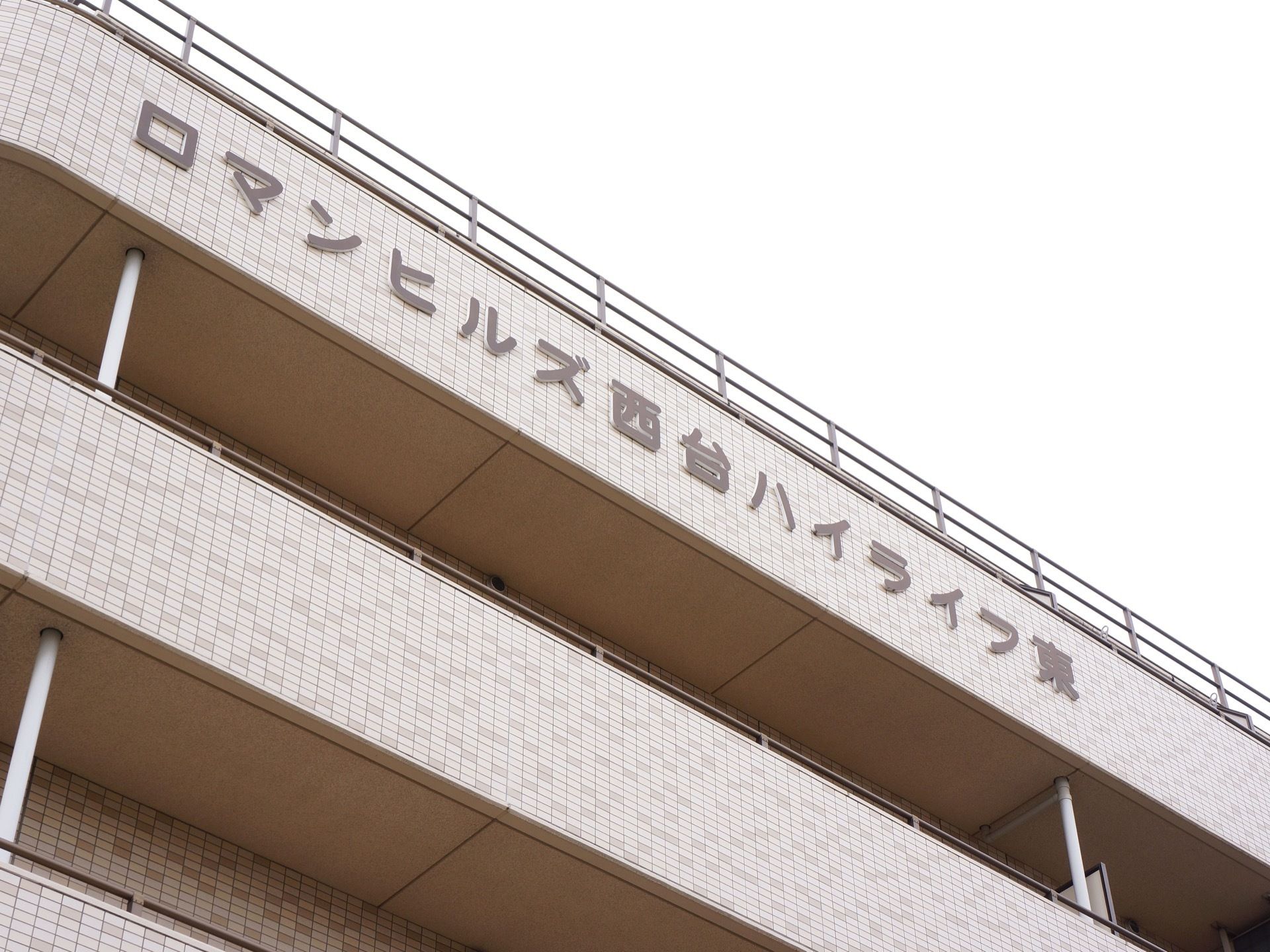 建物の最上階の壁に、施設名が付けられている。薄いベージュのレンガに茶色がかったグレーの文字が浮かび、落ち着いた雰囲気がある。
