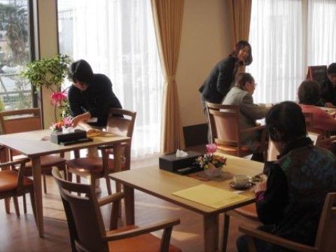施設職員に見守られ、テーブルの上で昼食をとる入居者たち
